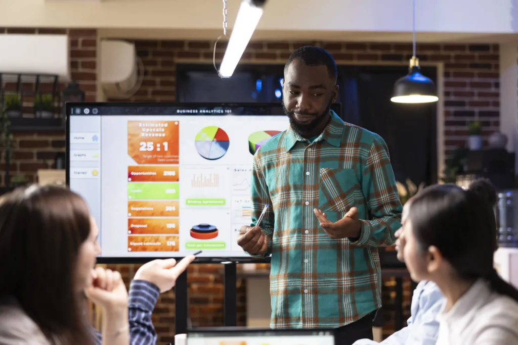 Marketing strategist presenting a business analytics dashboard to colleagues in a modern office.