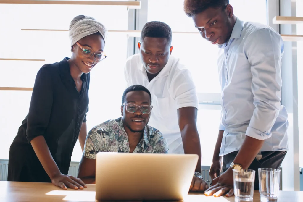 Diverse African team collaborating around a laptop in a bright office.